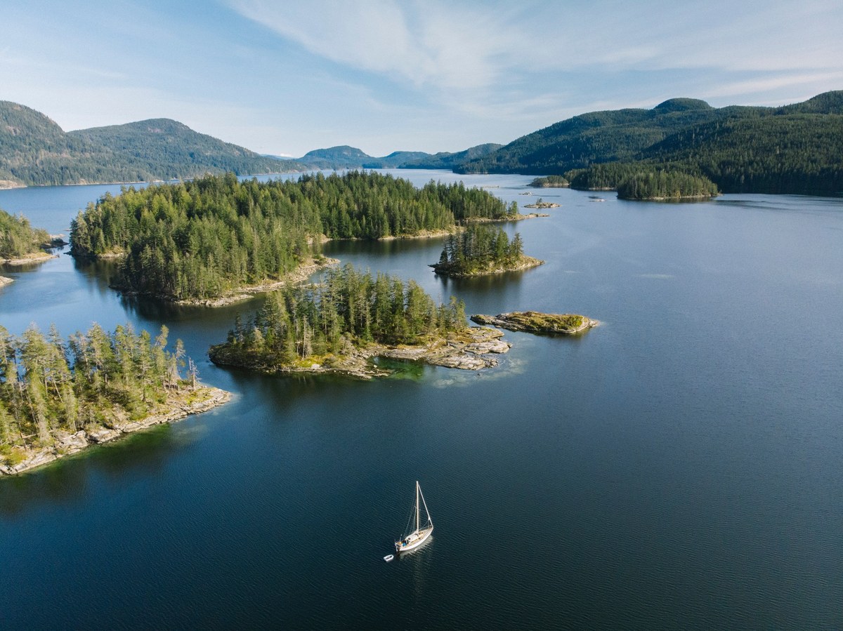 Jura seen from above, a small white boat among wooded islands in blue water